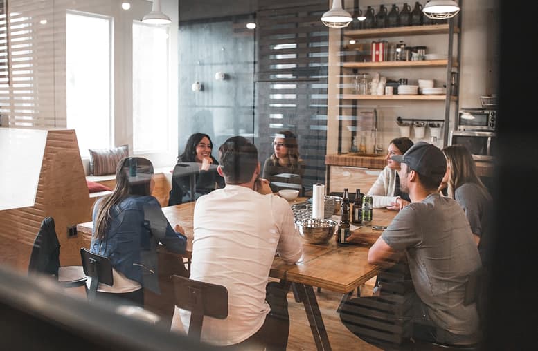 Group of people having a discussion around a table in an office setting.